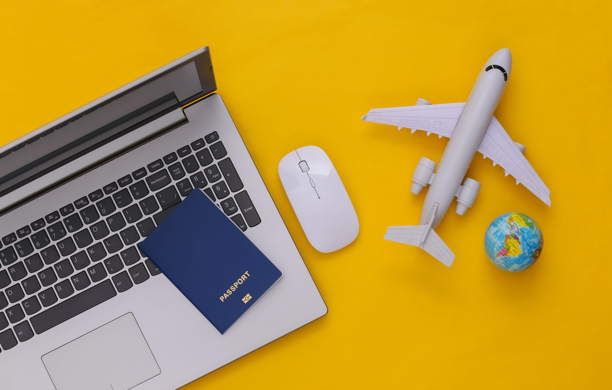 Laptop and travel accessories on a yellow background